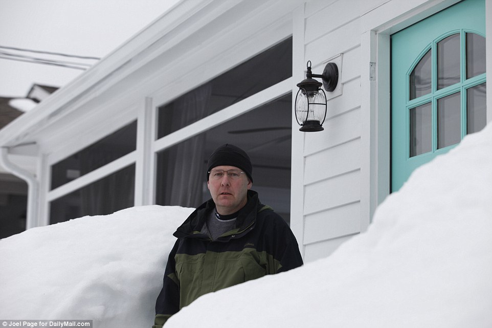 Not going away: Resident Brian Barrett outside his home where snow is still banked as high as the windows 